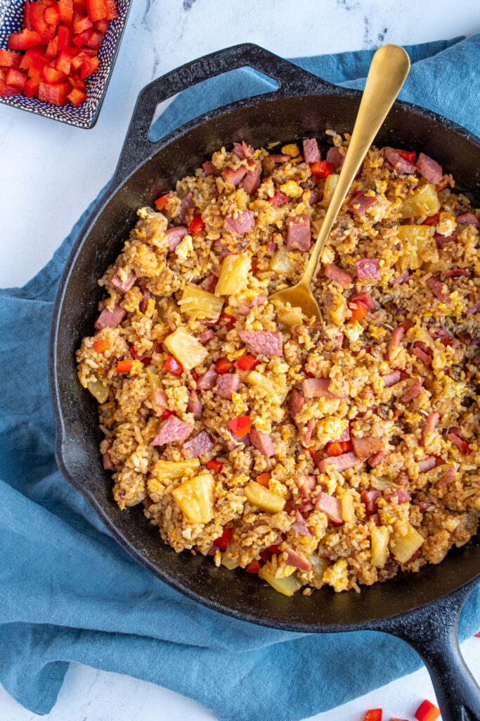 Close up of fried rice in a skillet with ham, pineapple, and red bell pepper.