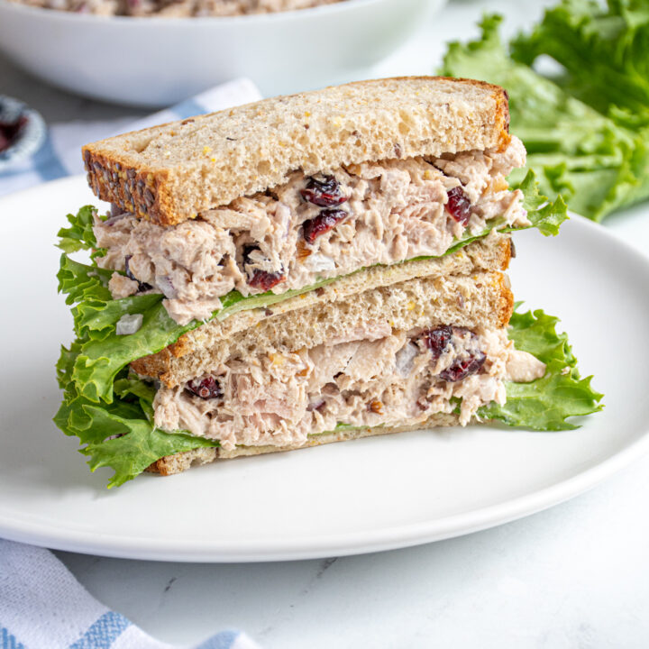 A tuna salad with cranberries sandwich cut in half and stacked to reveal the inside.