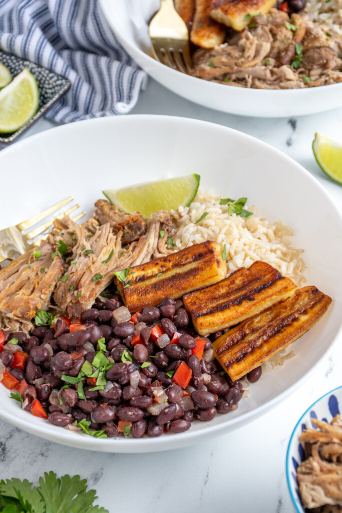 Close up of a large cuban bowl filled with rice, pork, black beans, and fried bananas.