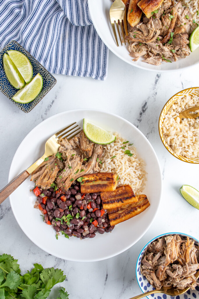 Overhead table view of bowl filled with cuban bowl recipe with rice mojo pork, black beans, and fried bananas.