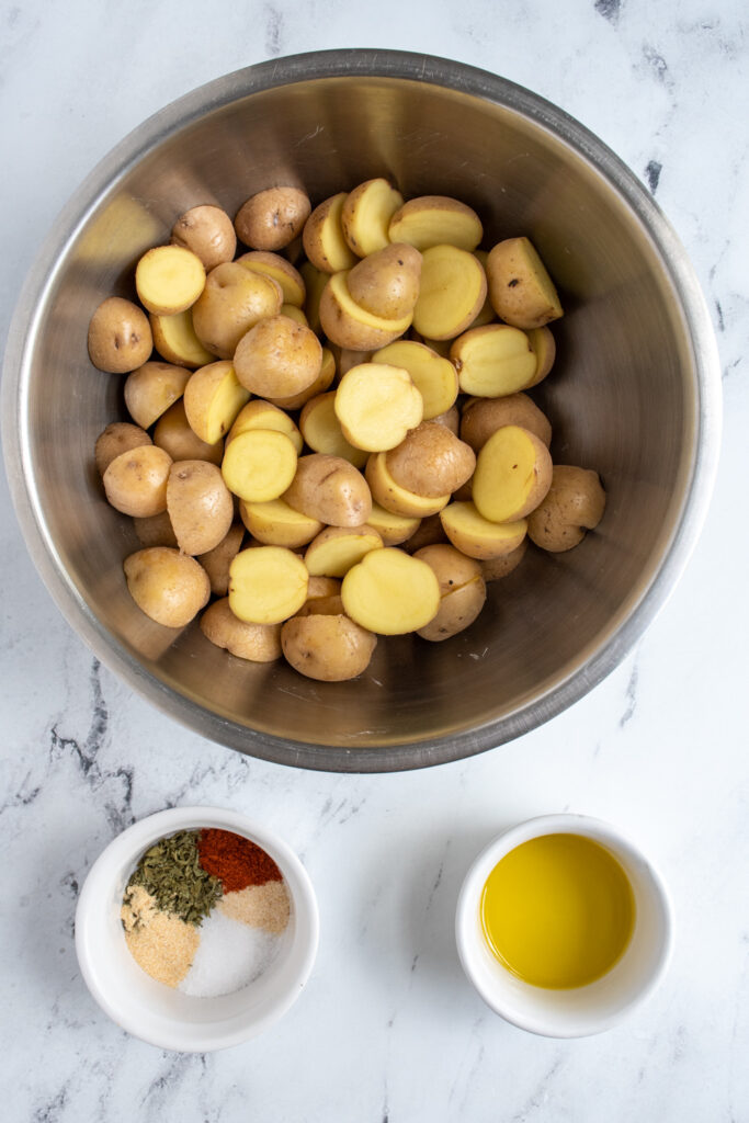 Ingredients needed to make air fryer home fries from baby potatoes all laid out on a tabletop.