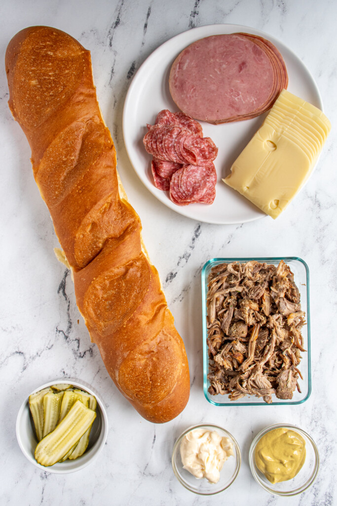 Overhead view of ingredients for making cuban sandwiches laid out on a tabletop.