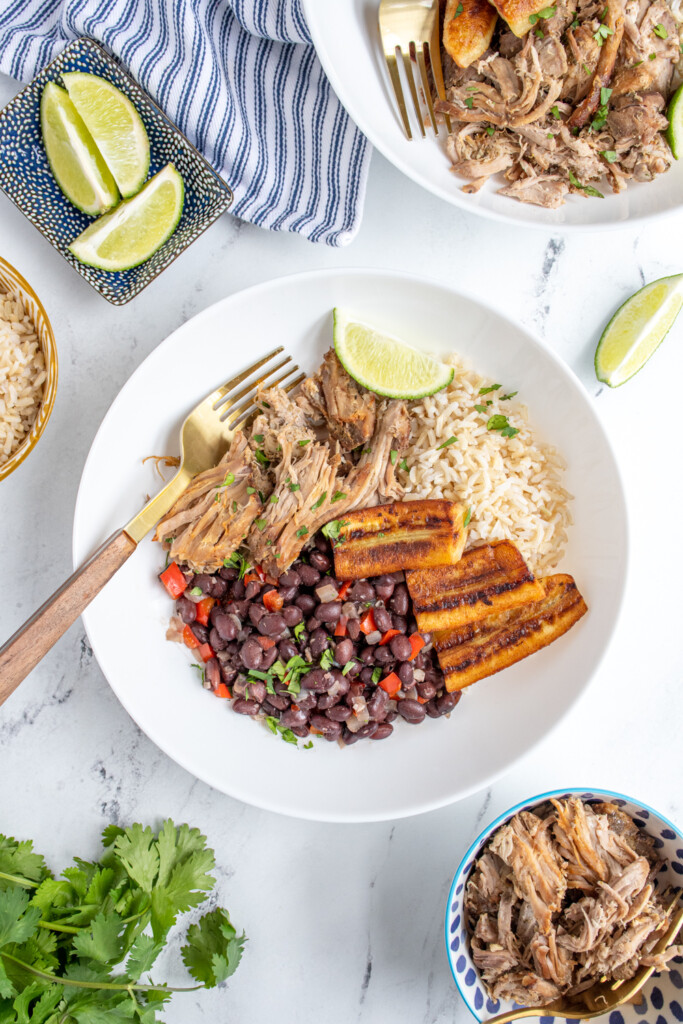 Overhead view of a cuban bowl filled with rice, mojo pork, black beans, and fried bananas.