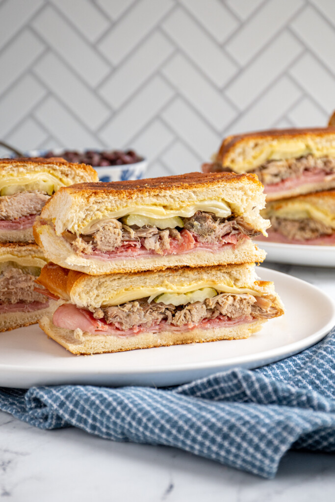 A stack of homemade Cuban sandwich halves showing of the ingredients on the inside.
