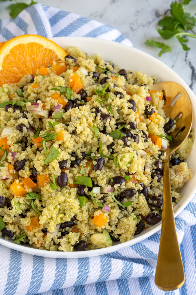 Close up of a large bowl of black bean quinoa salad with orange cilantro dressing garnished with orange slices and cilantro.