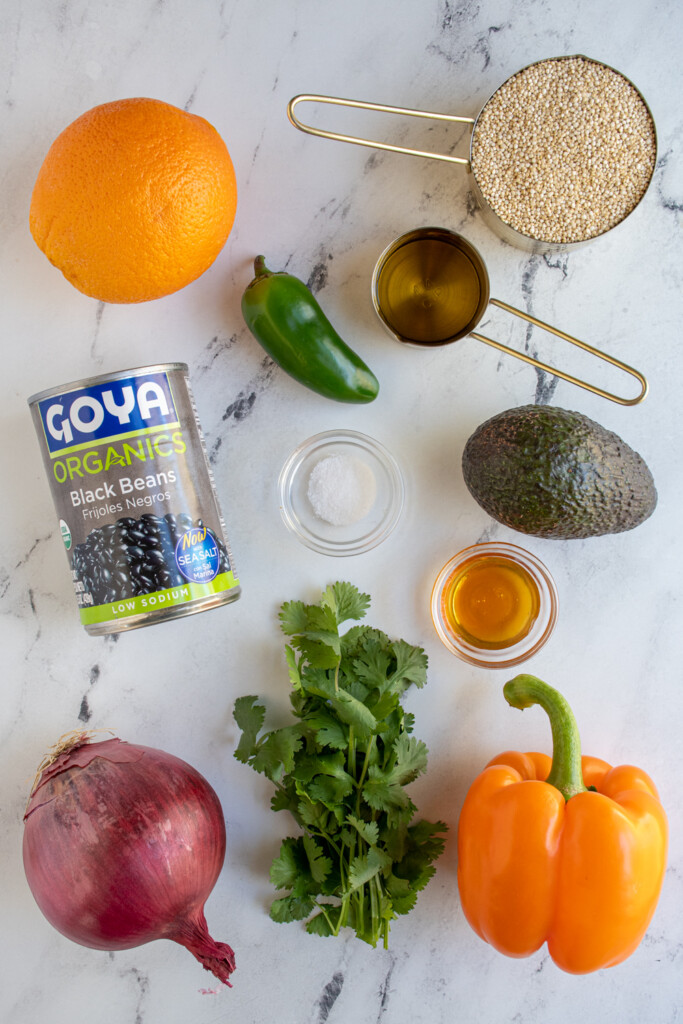 Ingredients to make black bean quinoa salad with orange cilantro dressing laid out on a tabletop.