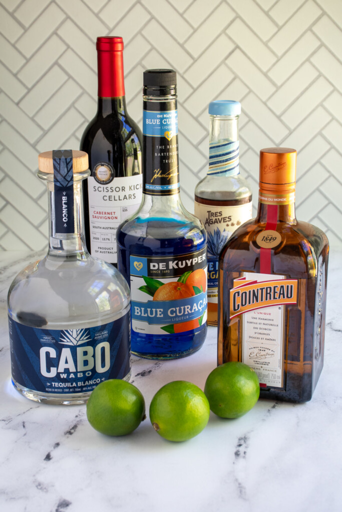 Ingredients needed to make red, white, and blue margaritas on a table top.