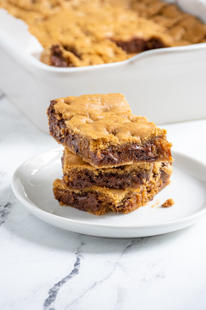 A small white plate with 3 whole wheat chocolate chip cookie bars stacked up.