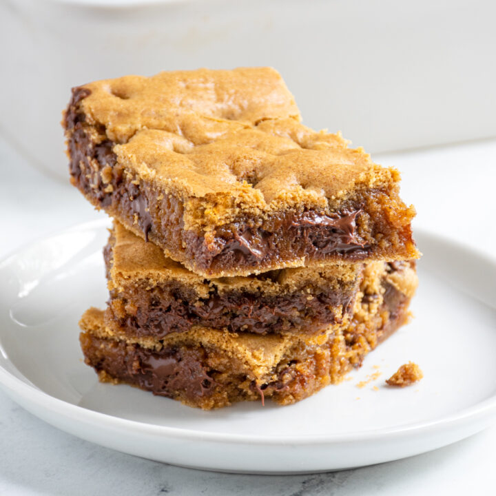 Close up of a stack of whole wheat chocolate chip cookie bars on a white plate with melty chocolate.