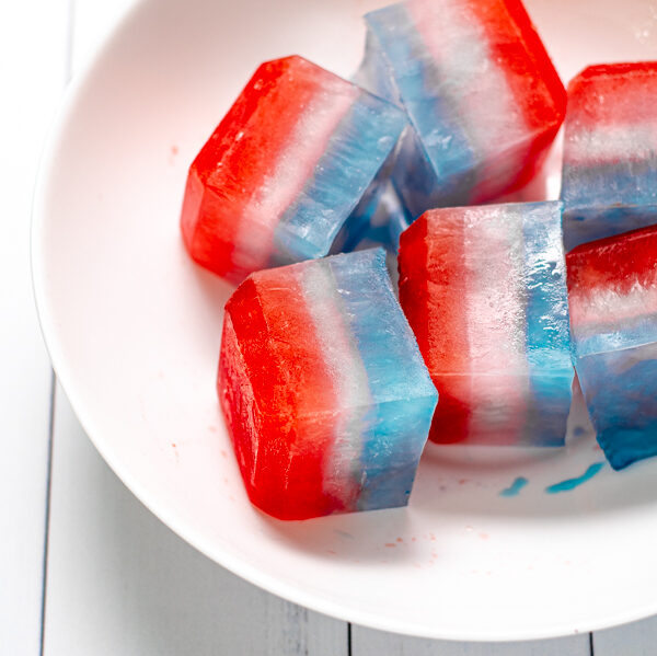 close up of layered red, white, and blue ice cubes in a large white bowl