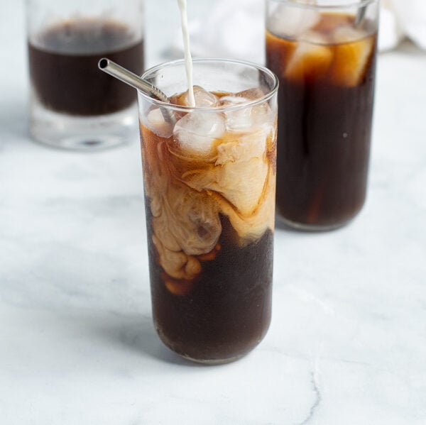 milk being poured into a glass of homemade cold brew coffee making milk and coffee swirls in the glass