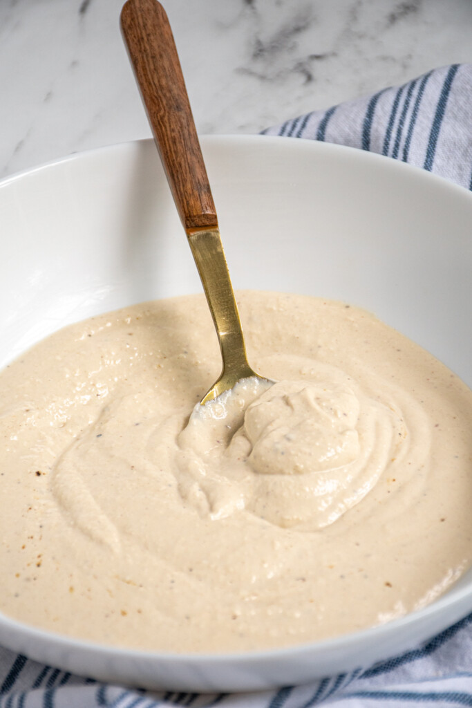 Bowl with Greek Yogurt Caesar Dressing and a spoon.