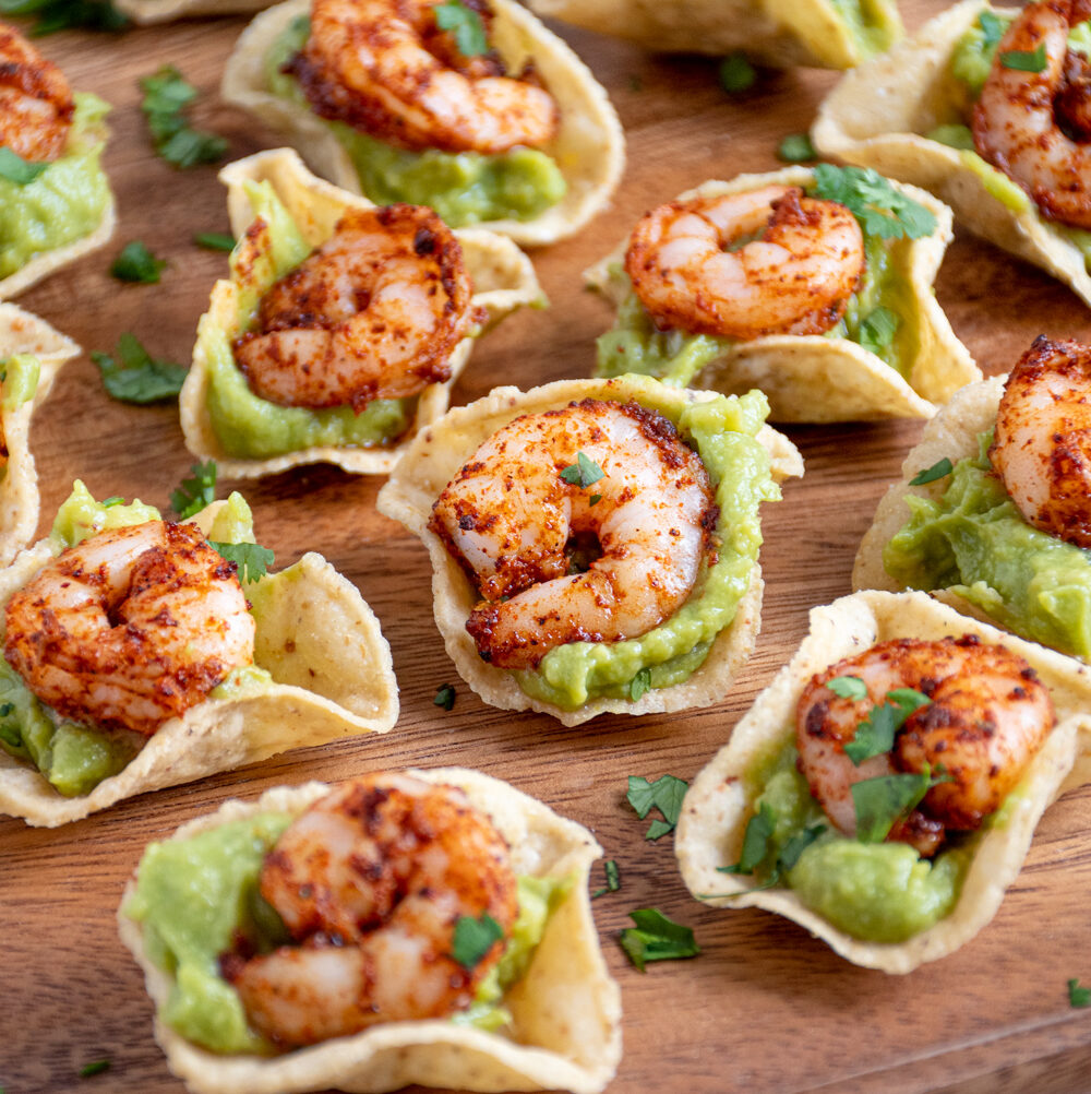 Close up of a shrimp guacamole bite on a platter showing of the juicy taco shrimp on top of guacamole.