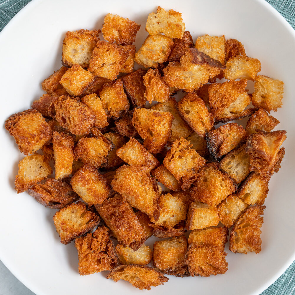 A white bowl filled with crunchy golden brown Air Fryer Croutons.