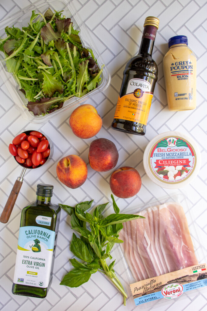 Ingredients for making grilled peach caprese salad with mozzarella laid out on a tabletop.