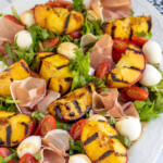 Pinterest pin with text overlay 'Grilled Peach Caprese Salad', image of a platter with grilled peach and mozzarella salad.