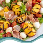 Pinterest pin with text overlay 'Grilled Peach Caprese Salad', image of a platter with grilled peach and mozzarella salad.