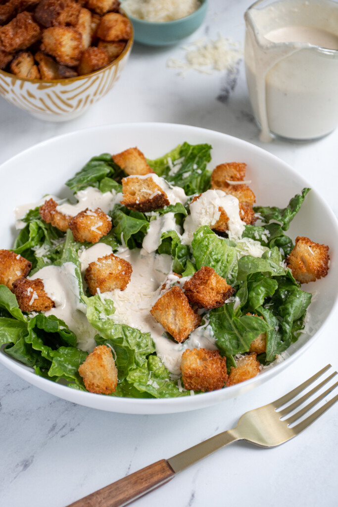 A salad with croutons topped with Greek Yogurt Caesar Dressing.