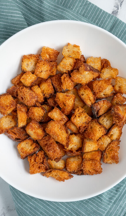 A white bowl filled with crunchy golden brown Air Fryer Croutons.