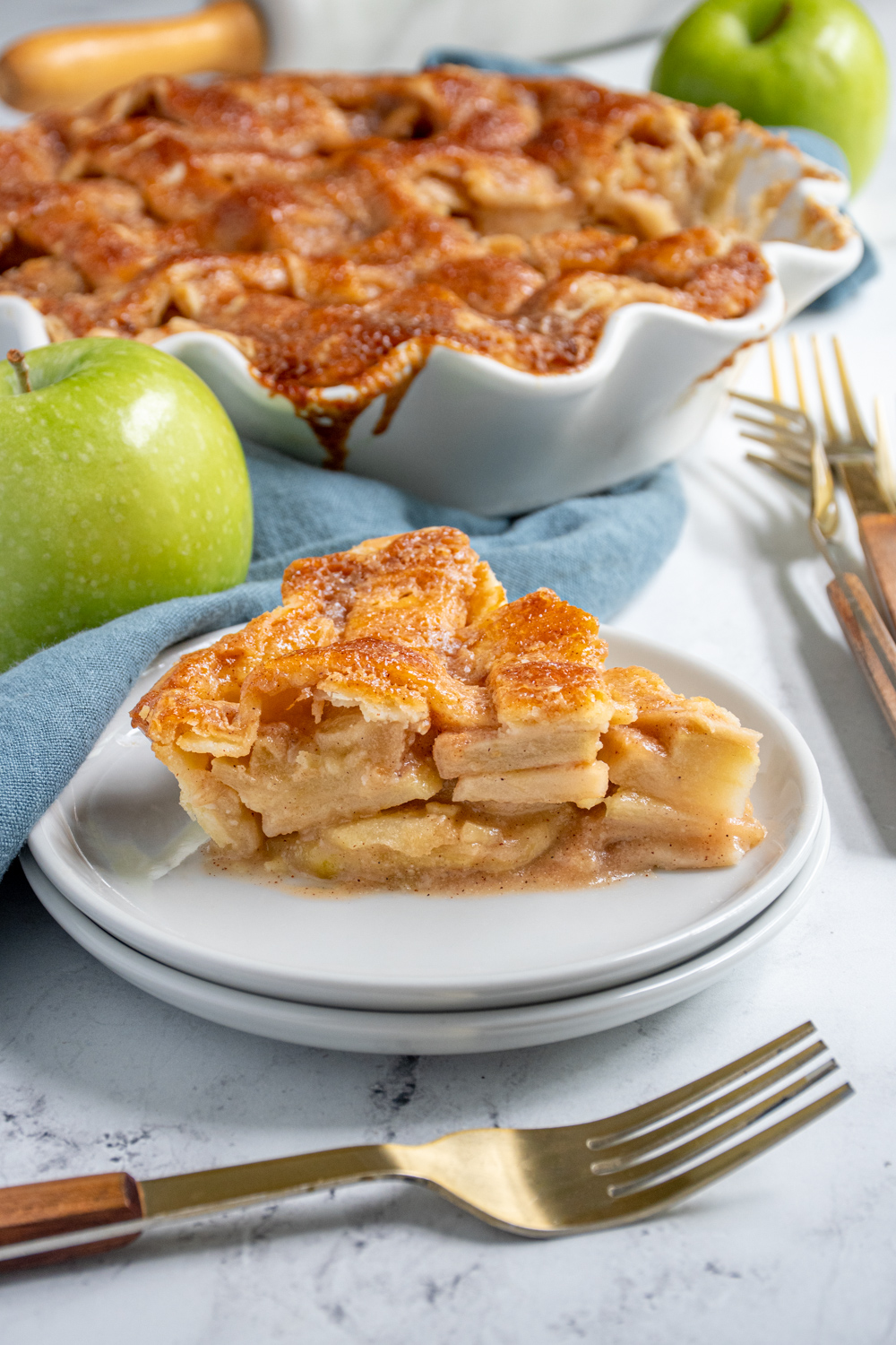 A slice of homemade apple pie on a plate showing of the apple inside and the lattice top.
