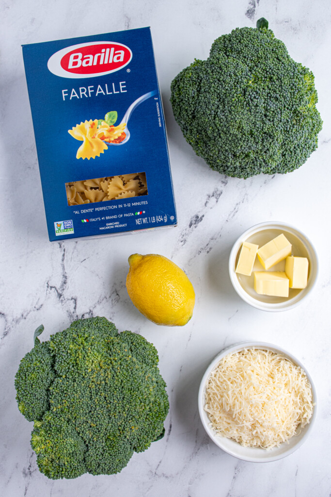 Ingredients needed to make bowties and broccoli laid out on a tabletop.