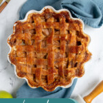 Pinterest Pin with text overlay 'Homemade Apple Pie', image of a pie on a blue towel next to some forks.