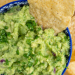 Pinterest pin with text overlay 'Simple Guacamole', image of a blu bowl filled with homemade guacamole with a tortilla chip.
