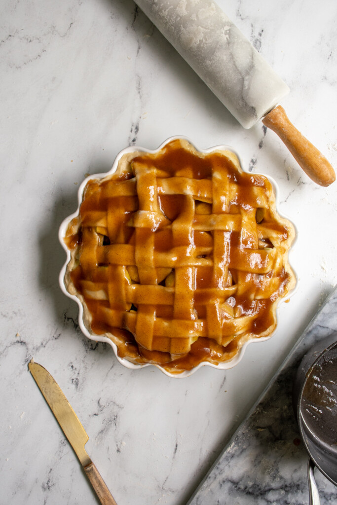 An apple pie right before it is about to go into the oven with the filling mixture poured over the top.