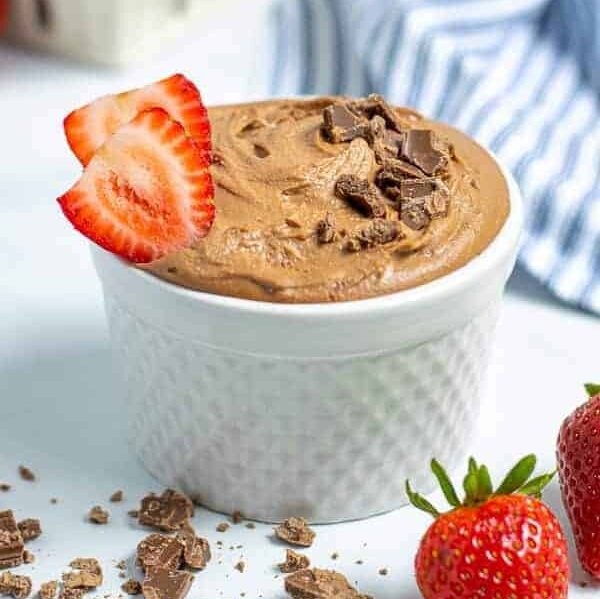 healthy best chocolate hummus in a white bowl sprinkled with chocolate shavings and slices of strawberries
