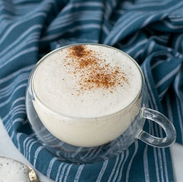 milk steamer drink in a clear mug with cinnamon sprinkled on top