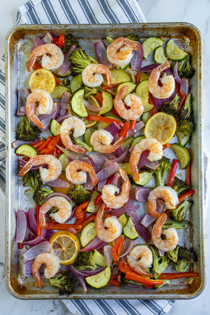 Overhead view of a sheet pan with shrimp and colorful vegetables.