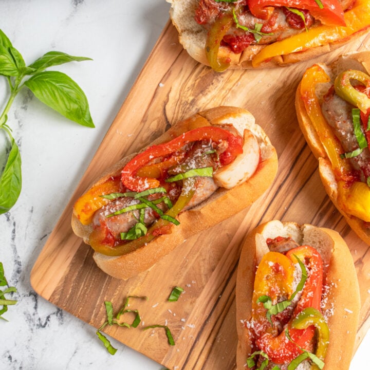Overhead view of a bunch of sausages in buns on a cutting board.