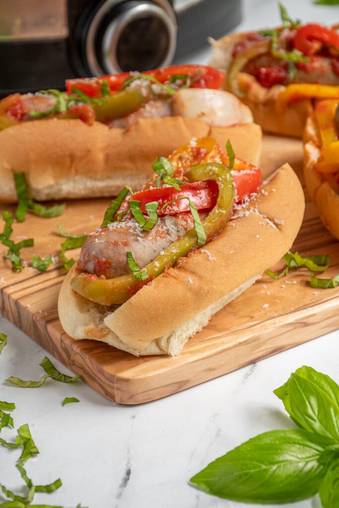Close up view of an Italian sausage in a bun with peppers and onions.