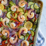 Pinterest pin with text 'Sheet Pan Shrimp & Veggies', image of a sheet pan with cooked pink shrimp and colorful vegetables.