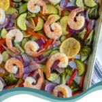Pinterest pin with text 'Sheet Pan Shrimp & Veggies', image of a sheet pan with cooked pink shrimp and colorful vegetables.