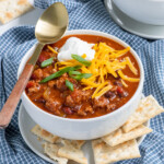 Pinterest pin with 'The Schmidty Wife' Logo, image of white bowl with chili and garnishes.