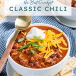 Pinterest pin with text 'the best Crockpot Classic Chili', image of white bowl with chili and garnishes.