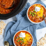 Pinterest pin with text 'the best Crockpot Chili', image of white bowl with chili and garnishes.