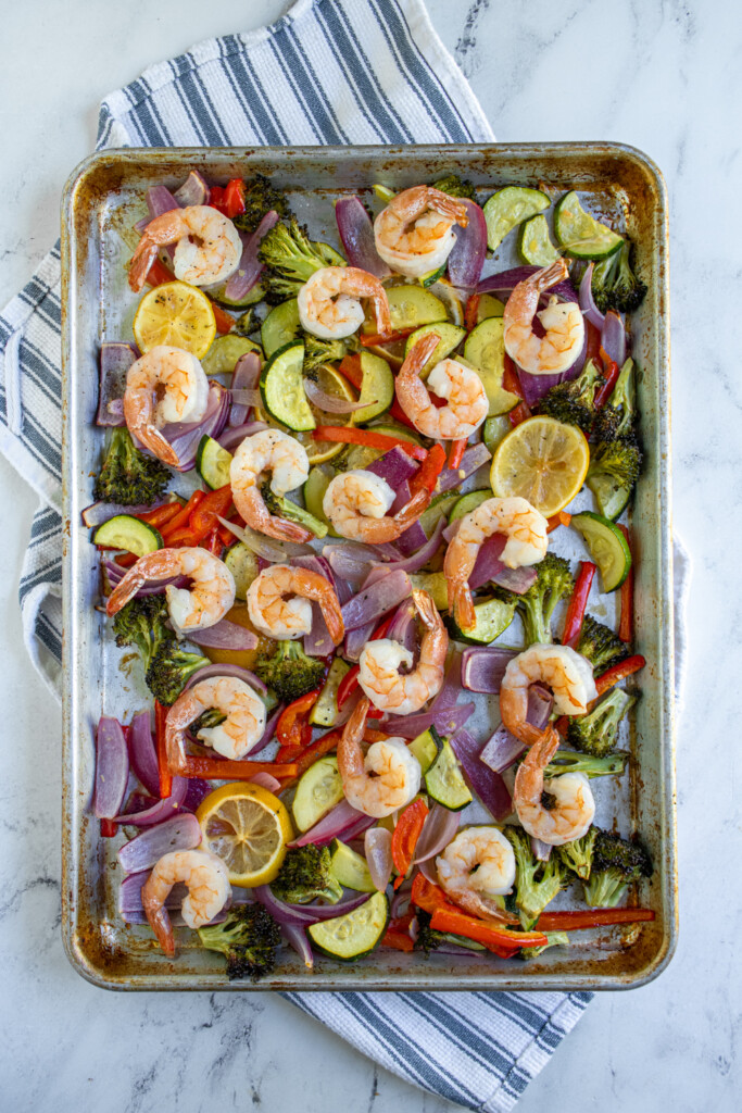 A sheet pan with baked shrimp and vegetables.