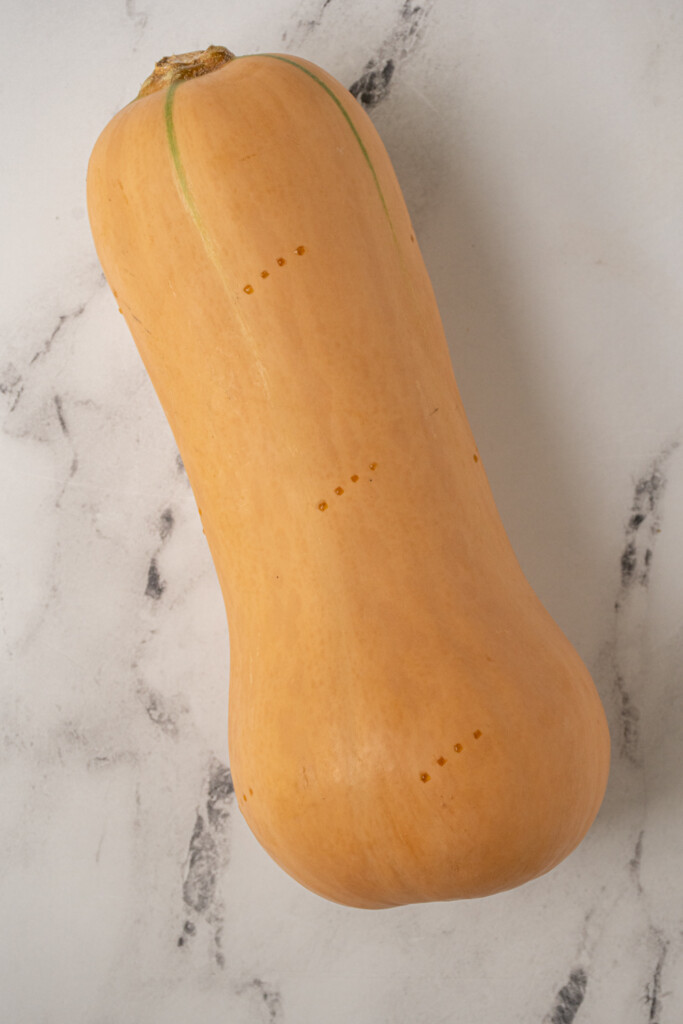 A butternut squash with fork holes poked in the skin.