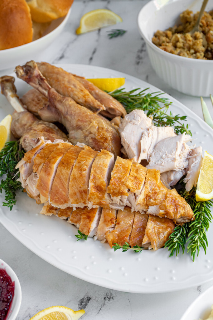 A carved thanksgiving turkey on a platter showing off sliced breast meat.