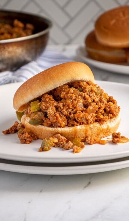 A bun filled with ground turkey sloppy joes on a plate.