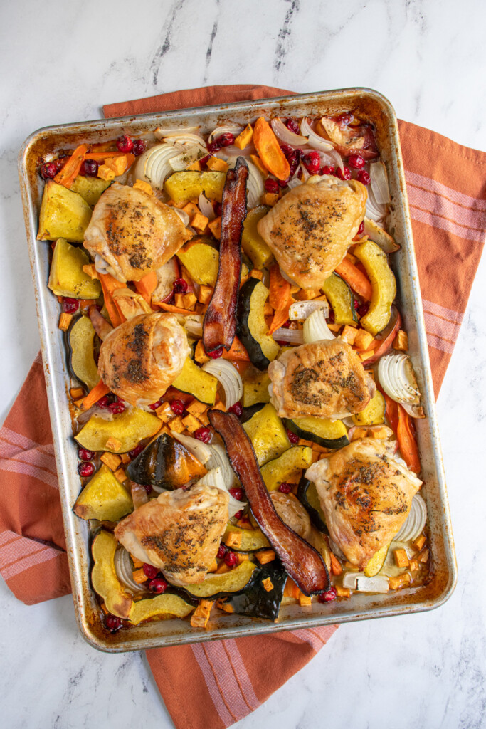Overhead view of one pan autumn chicken dinner with squash, cranberries, onions, chicken, and bacon.