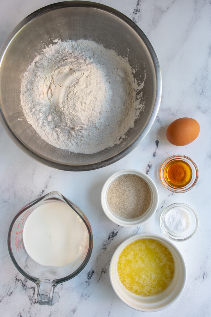 Ingredients needed to make homemade soft dinner rolls laid out on a table.