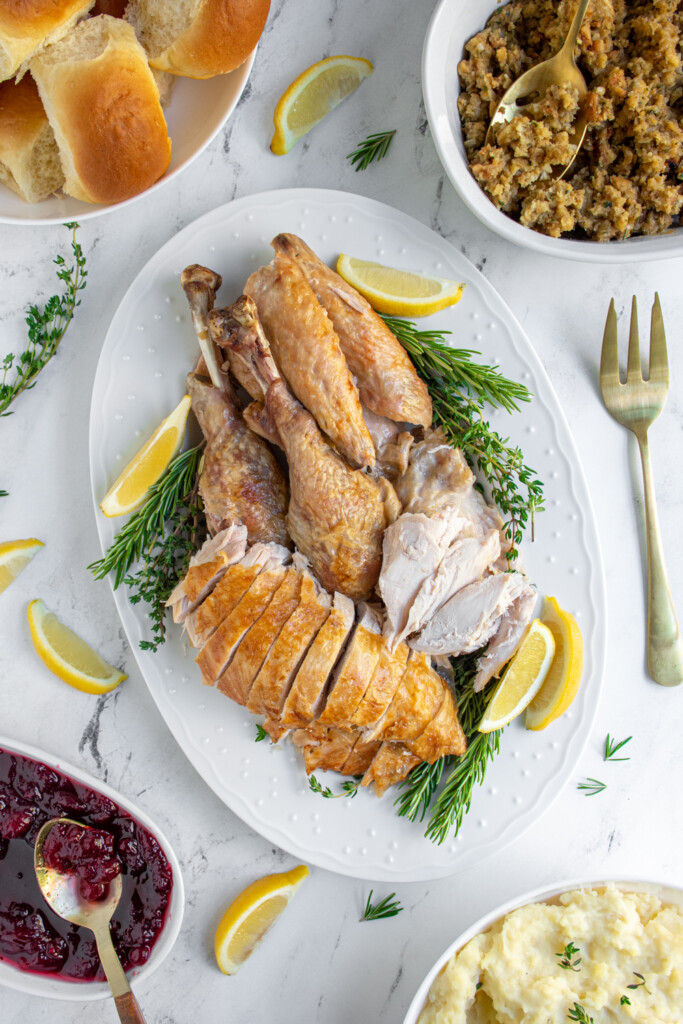 Overhead view of a platter with a carved Turkey with golden brown skin and juicy white meat.