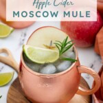 Pinterest pin with text overlay 'Apple Cider Moscow Mule', image of a copper mug full of apple cider mule garnished with apple, rosemary, and lime.