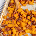 Pinterest pin with text overlay 'Maple Roasted Butternut Squash', image os a sheet pan with cooked squash and pecans.