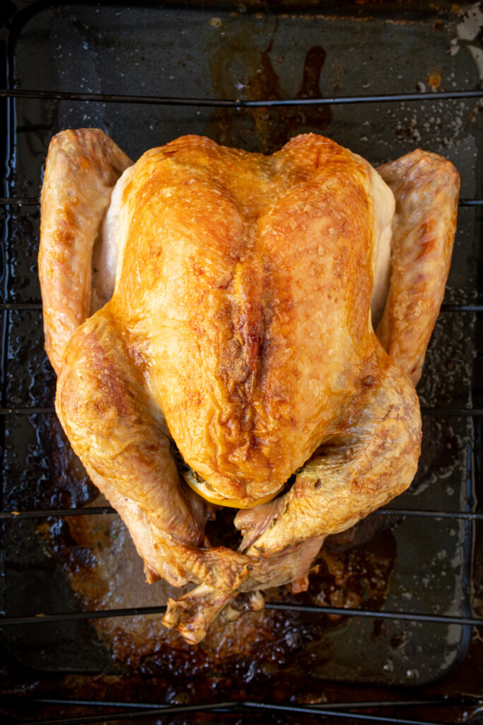 Overhead view of a golden brown turkey fresh out of the oven in a black roasting pan.
