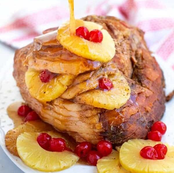 glaze being poured over a spiral ham with pineapple slice