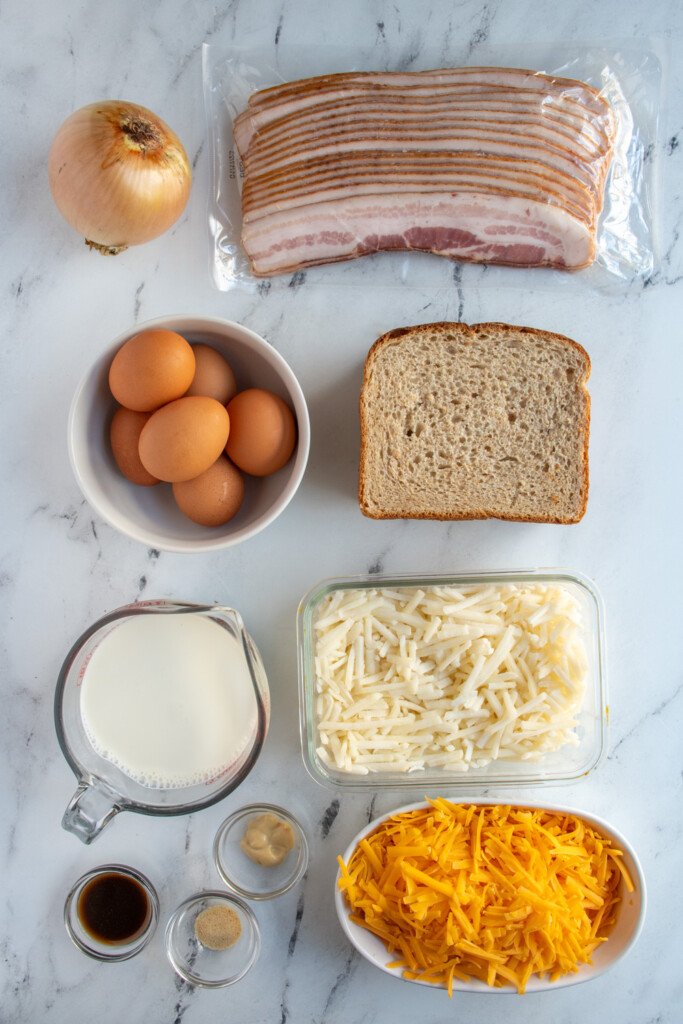 Ingredients needed to make breakfast casserole with hash browns and bacon laid out on a table top.